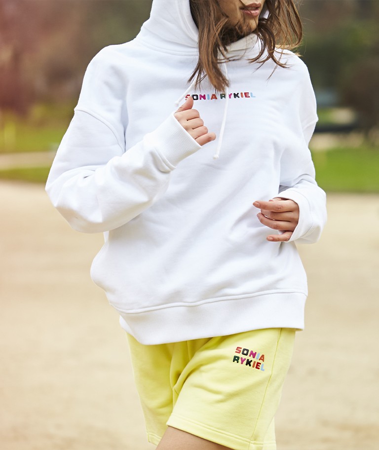 A woman wearing the signature multicolor oversized hoodie and the cotton short shorts
