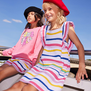 Girls wearing a multicolored striped dress and a pink sweatshirt