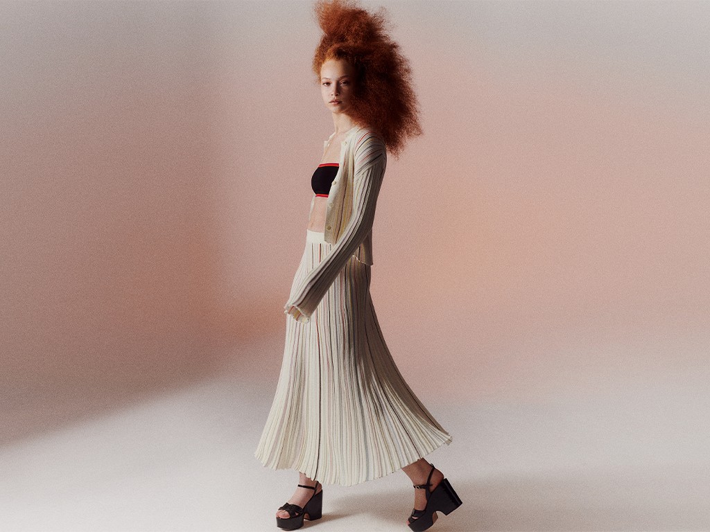 A woman wearing the multicolor striped long pleated skirt with the multicolor striped pleated shirt